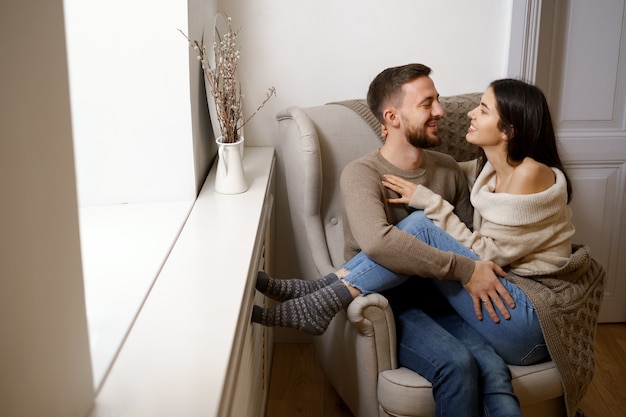 Two people sitting close together on a couch, with one gently holding the other person's hand in a supportive gesture.